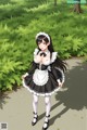 A woman in a maid outfit is walking down a path.