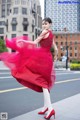 A woman in a red dress is dancing in the street.