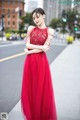 A woman in a red dress standing on a city street.