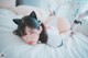 A woman laying on top of a bed wearing cat ears.