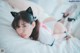 A woman laying on top of a bed wearing cat ears.