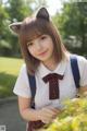 A girl in a school uniform with a cat ears on her head.