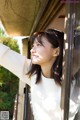 A woman looking out of a window with her hand up.