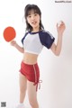 A woman holding a ping pong paddle and a ball.