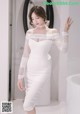 A woman in a white dress standing in front of a mirror.