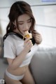 A woman in a white shirt eating a banana.