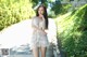 A woman in a white dress standing on a wooden walkway.