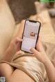 A woman sitting on a couch holding a cell phone.