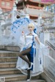 A woman in a white and blue dress holding an umbrella.