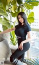 a woman sitting on top of a couch next to a plant