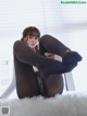 A woman sitting on top of a white fur covered bed.