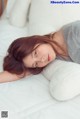 A woman laying on top of a bed next to a pillow.