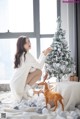 A woman sitting on a bed next to a christmas tree.