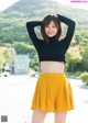 A woman in a black top and yellow skirt posing for a picture.