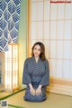 A woman in a kimono sitting on the floor in front of a window.