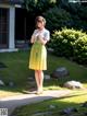 A woman in a yellow dress standing in front of a house.