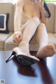 A woman sitting on top of a table next to a pair of shoes.