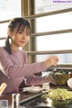 A woman in a kitchen preparing food with chopsticks.