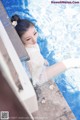 A woman in a white dress sitting in a pool.