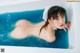 A naked woman in a bathtub with a white towel on her head.