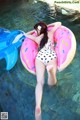 A woman in a bikini laying on an inflatable donut in the water.