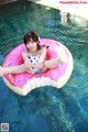 A woman in a bathing suit sitting on an inflatable donut in a pool.