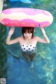 A woman in a bathing suit holding an inflatable donut over her head.