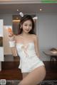 A woman in a white dress holding a carrot.