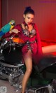 A woman sitting on a motorcycle with a parrot on her shoulder.