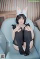 A woman sitting on a blue chair wearing bunny ears.