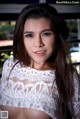 A woman in a white lace top posing for a picture.