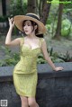 A woman in a yellow dress and straw hat posing for a picture.