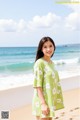 A woman standing on a beach next to the ocean.