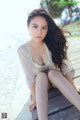 A woman sitting on a wooden bench on the beach.