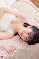 A woman laying on top of a bed in a white dress.