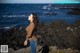 A woman standing on a rocky beach next to the ocean.