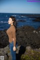 A woman standing on a rocky beach next to the ocean.