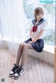 A woman in a school uniform sitting on a window sill.