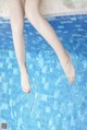 A woman's legs in a swimming pool with her feet in the water.