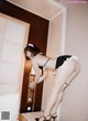 A woman in a black and white lingerie leaning against a wall.