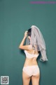 A woman in a white bra and panties with a veil over her head.