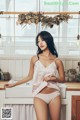 A woman standing in a kitchen next to a sink.