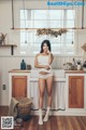 A woman standing in a kitchen next to a sink.