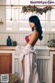 A woman standing in a kitchen next to a sink.