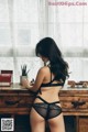 A woman in a black lingerie sitting on a dresser.