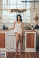 A woman standing in a kitchen next to a window.