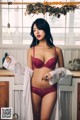 A woman in a red bra and panties standing in a kitchen.