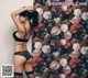 A woman in lingerie leaning against a wall with flowers.