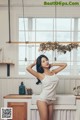 A woman standing in a kitchen next to a sink.