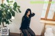 A woman sitting on a chair next to a plant.